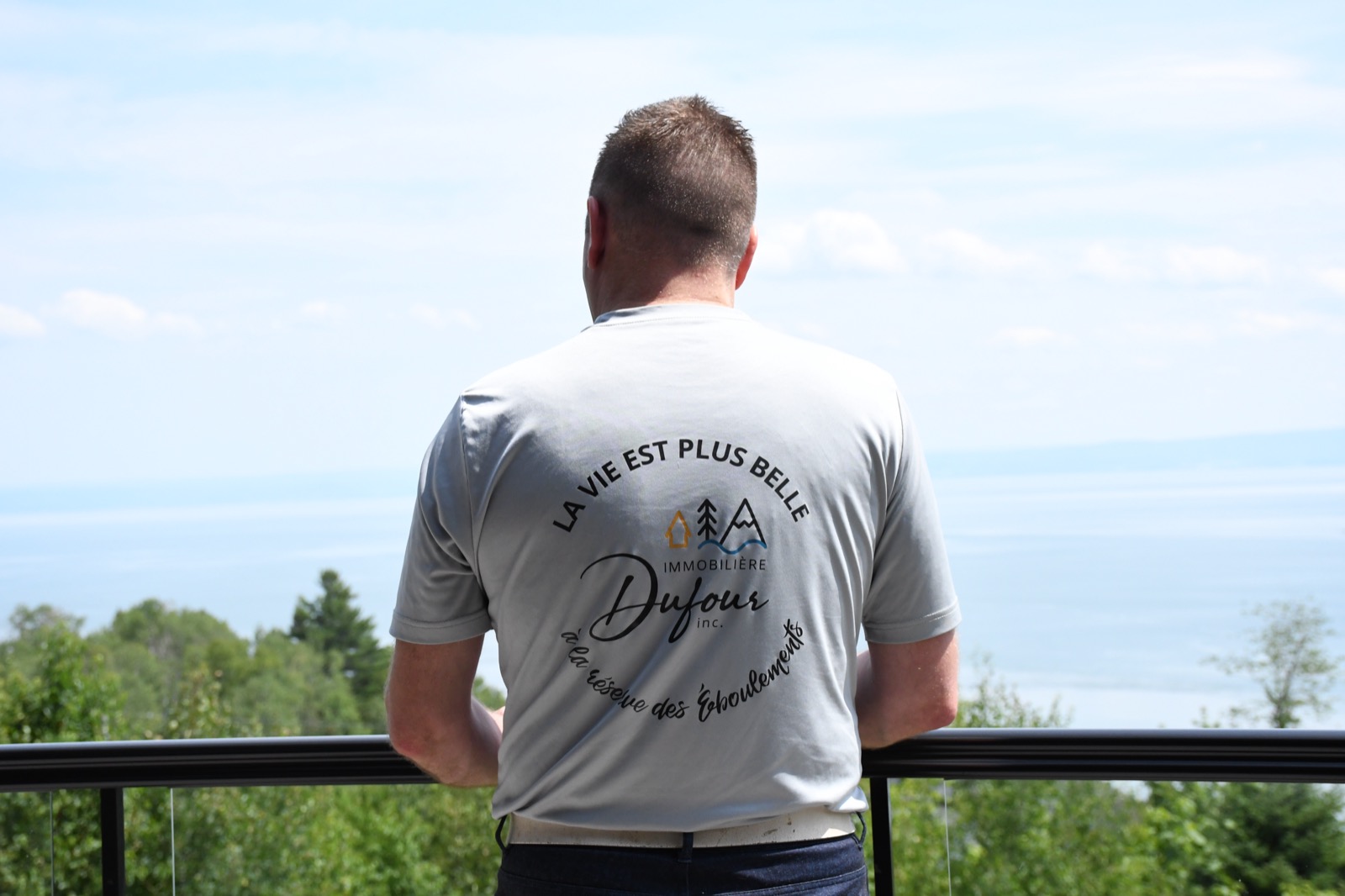 Homme portant le chandail Immobilière Dufour, de dos avec vue sur le fleuve