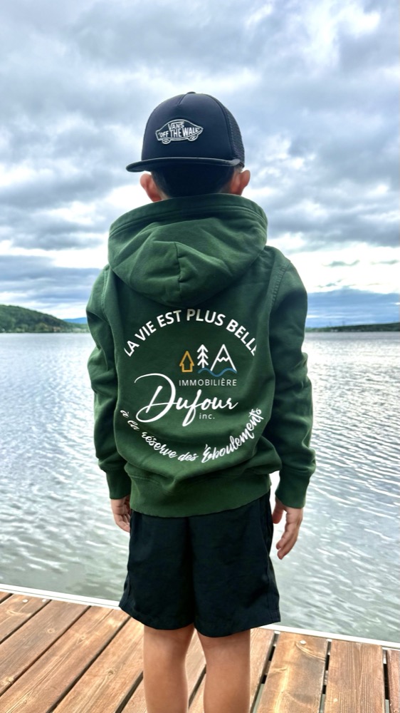 Enfant portant le chandail à capuchon Immobilière Dufour, de dos
